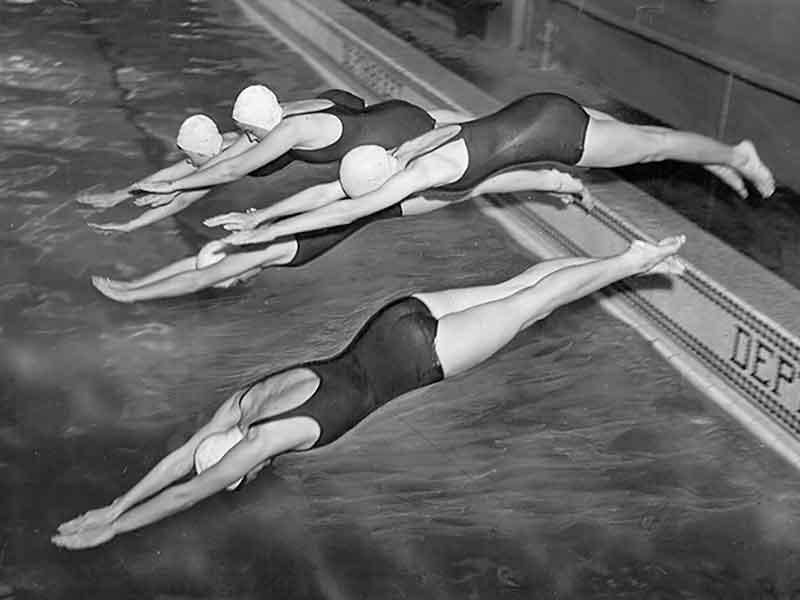 Members of the Newcomb College women’s synchronized swim team, the Barracudas, dive into the Newcomb swimming pool in 1946