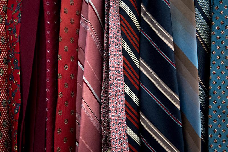 A collection of ties hangs neatly in order of hue. A close-up view of the costume shop reveals the importance of organization.