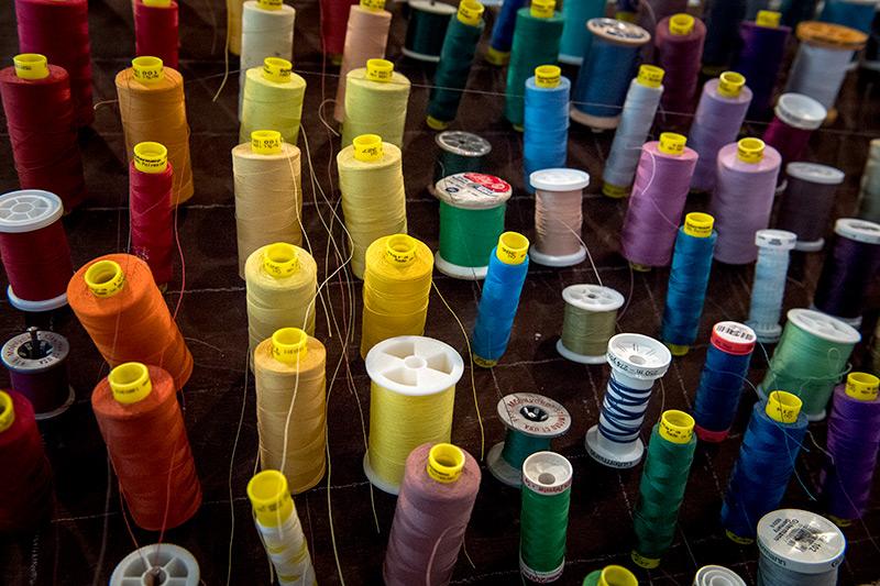 Spools of thread are arranged according to the order of colors that make up a rainbow. A close-up view of the costume shop reveals the importance of organization.