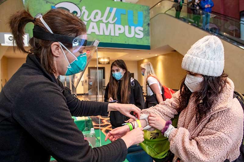 Emily Holt with Campus Health cuts off Joelle Friedman's yellow wristband after replacing it with a green one Emily Holt with Campus Health cuts off Joelle Friedman's yellow wristband after replacing it with a green one