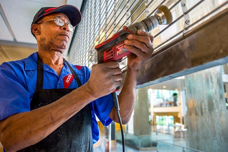 Nathaniel Robinson, a utilities specialist with Sodexo, buffs the Lavin-Bernick Center food court’s metal door to make it “look like new” in preparation for its re-opening on August 15th.