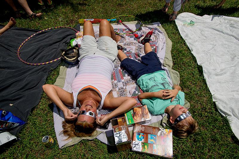Nia Quinn and her son Jay Quinn take in the eclipse at The Fly in uptown New Orleans. Locals are captivated by the awe-inspiring solar eclipse.
