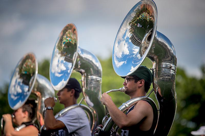 Joe Foster, right, stands at attention to support the weight of his sousaphone. The Tulane University Marching Band (TUMB) braves the August heat and humidity to practice marching basics during the annual band camp on Brown Field.