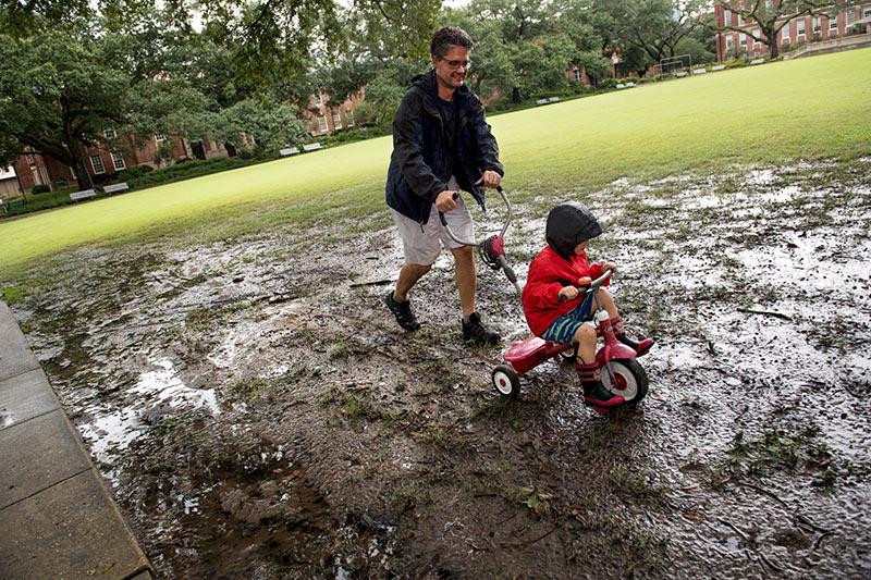 Victor Holtcamp, assistant professor in the department of theatre and dance, takes a detour from the sidewalk as he pushes his son Theo on Newcomb quad. Members of the Tulane community took advantage of a day off Tuesday due to possible heavy rain and flooding from Harvey.