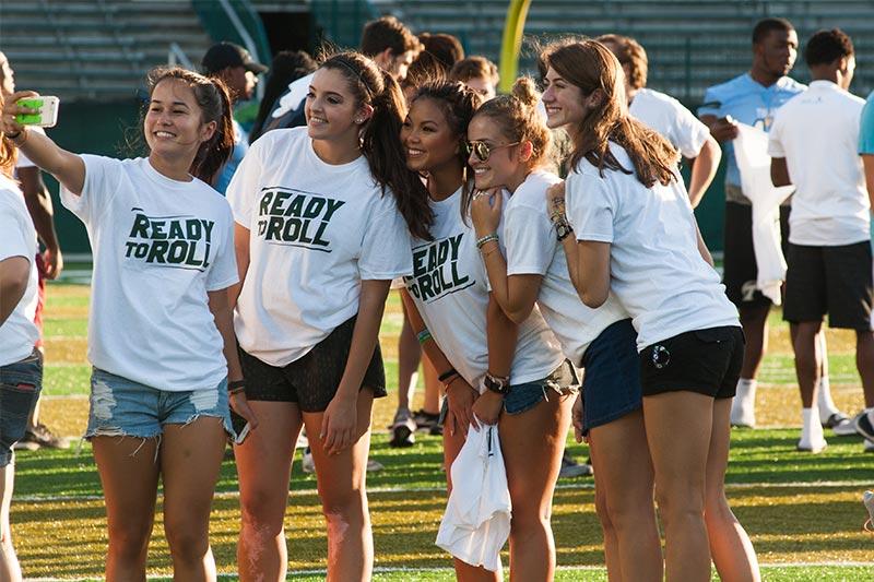 Spirited students huddle together on Benson Field for a quick selfie during the annual Yell For Yulman event Yell For Yulman introduces first-year students to the Tulane football team and Green Wave spirit.