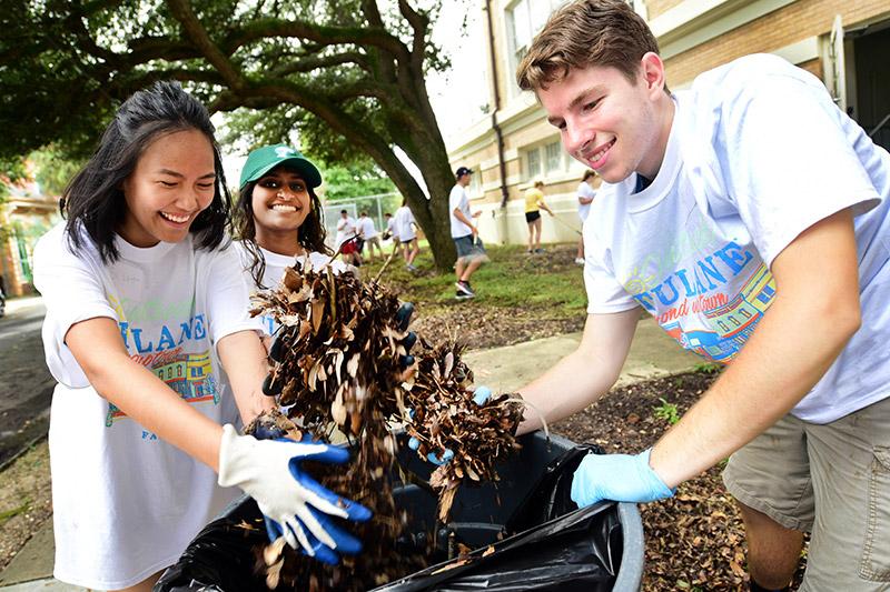 Business TIDES classmates Su Latt Swe Zin, left, Nadia Kumar, center, and Alex Twiford bag leaves while cleaning the grounds at Renew Cultural Arts Academy at Live Oak Elementary. Students participate in the 28th annual Outreach Tulane.