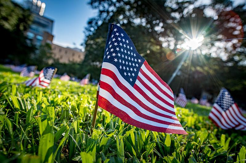 Several hundred American flags fly on the academic quad in commemoration of lives lost during the terror attacks of September 11th, 2001. College Democrats and Republicans unite to honor lives lost on 9/11.