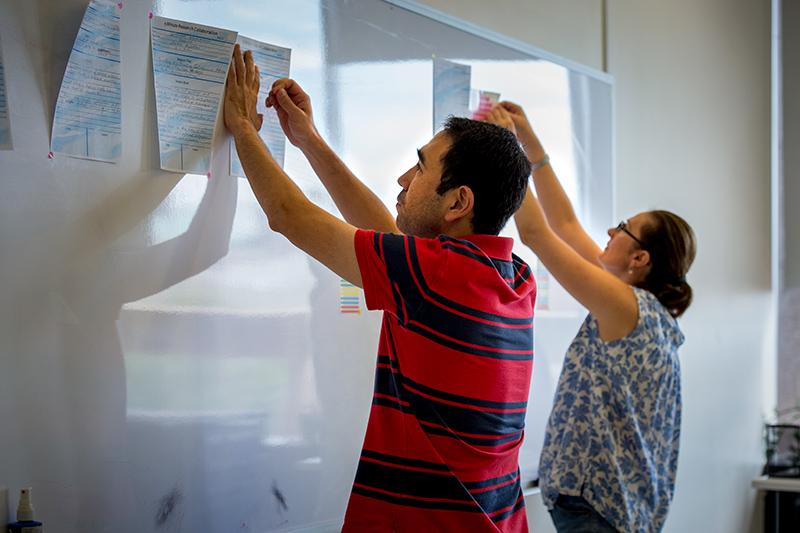Diyar Talbayev, left, associate professor in the department of physics, and Zhigunova post their project proposals for the group to review. Faculty race to come up with creative, cross-discipline research projects.