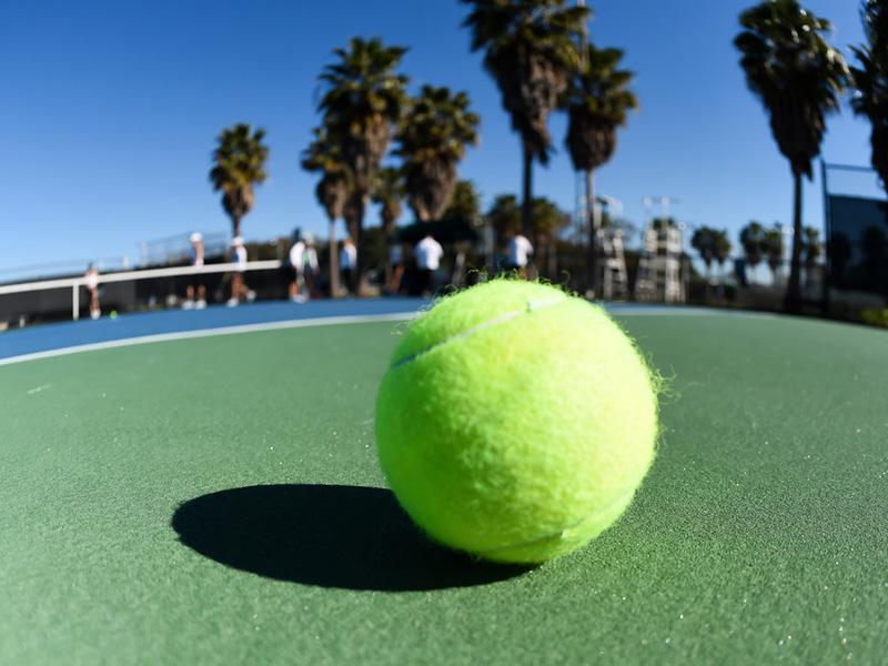 Wide angle picture of tennis ball sitting on a court.