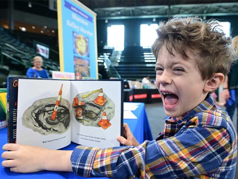 An ecstatic young reader enjoys the book “Goodnight Pothole” at Family Day.  