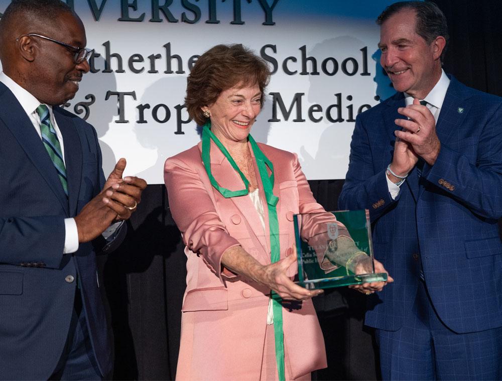 Celia Scott Weatherhead holds a glass plaque bearing the new name of the school. 