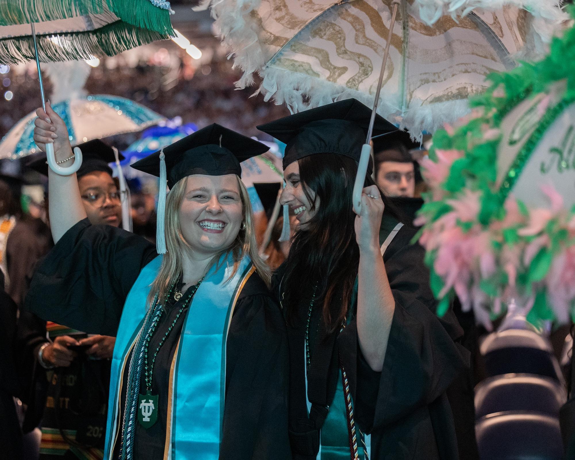 Grads share a moment while holding umbrellas Grads share a moment while holding umbrellas