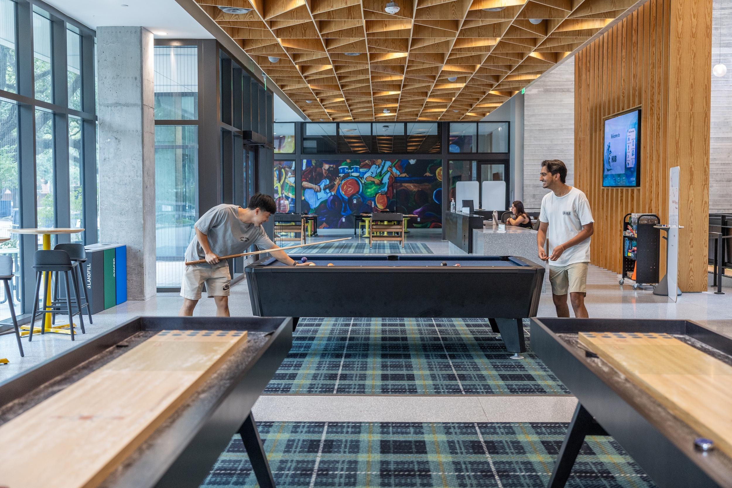 Students play pool in the common area of a dorm