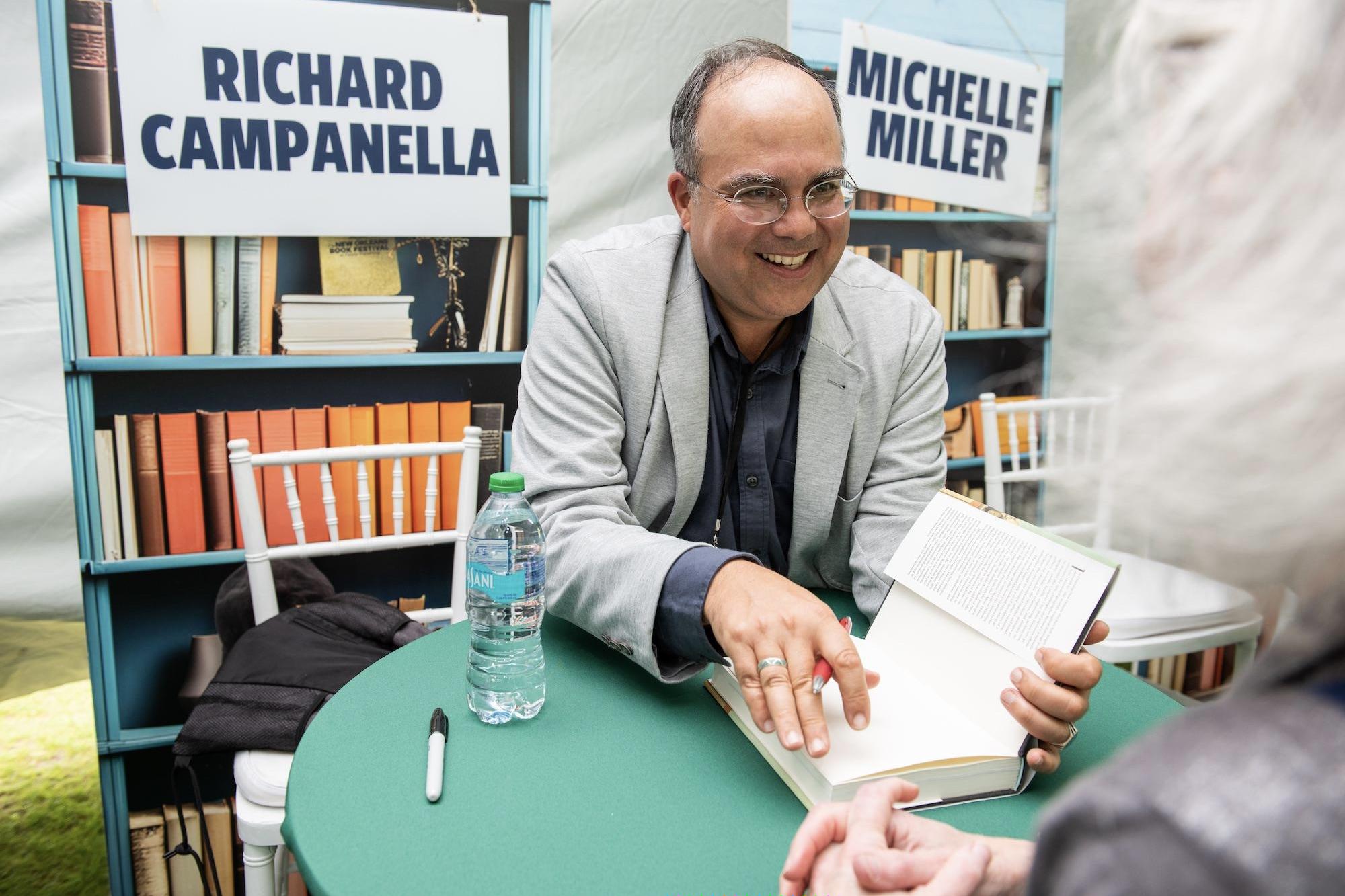 Smiling author Richard Campanella signs a book for a reader.