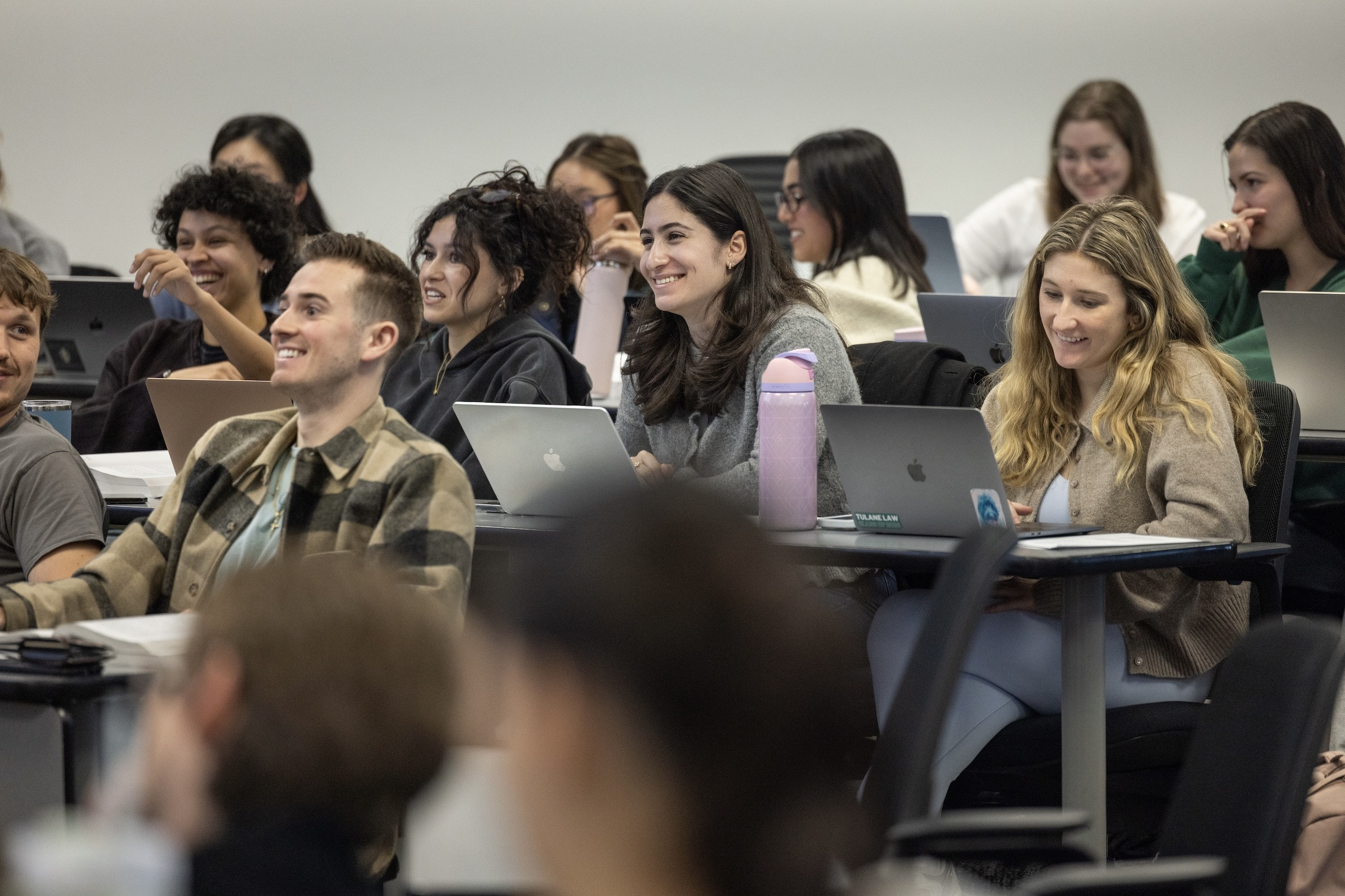 Students smiling and laughing in a classroom with laptops.