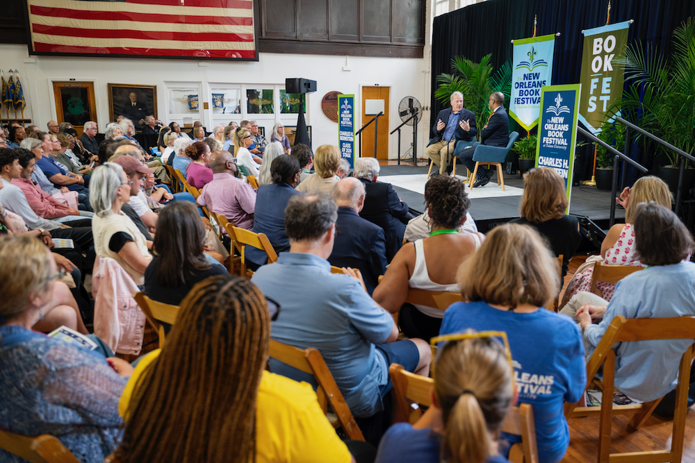 Indoor event with an audience watching two men on stage for a panel discussion at Book Fest 2025.