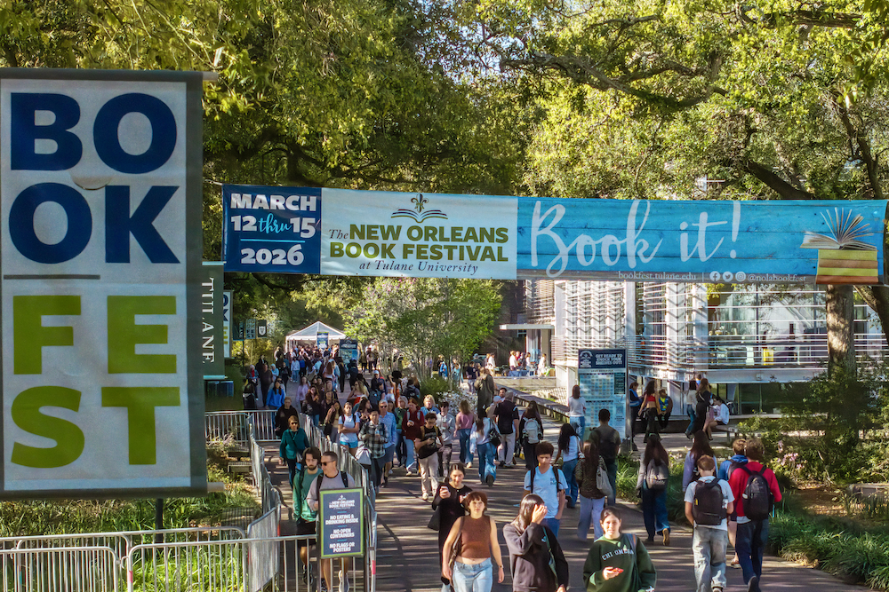 New Orleans Book Festival crowd walking outdoors, with "BOOK FEST" signs.