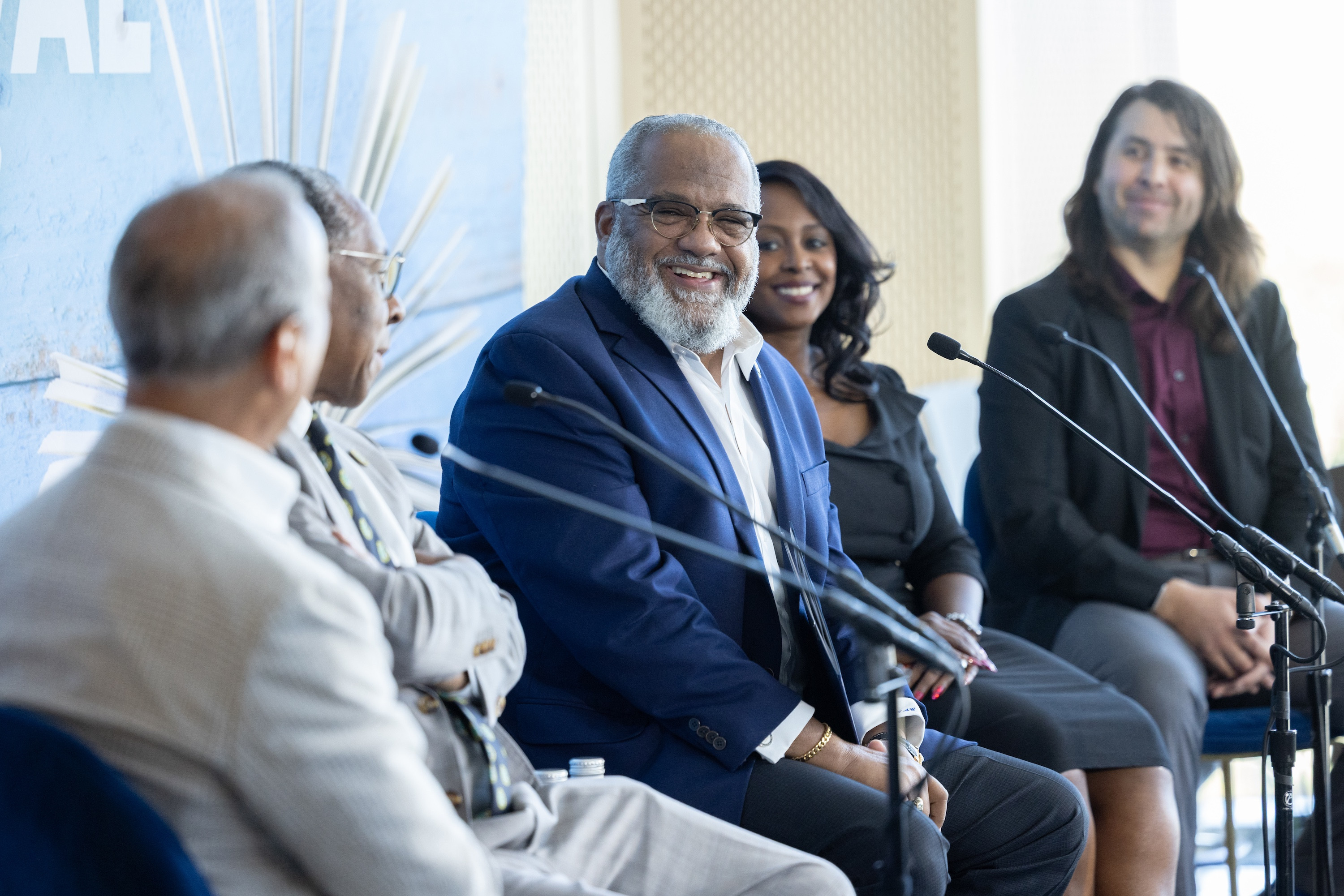 Panel of five people seated, some smiling, with microphones.