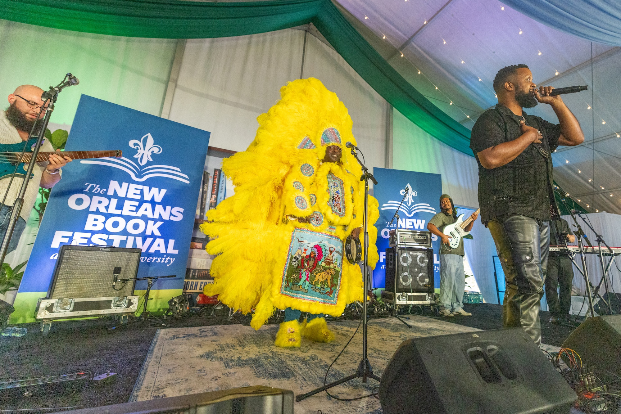 Mardi Gras Indian in yellow suit performs with a singer and musicians at New Orleans Book Festival.