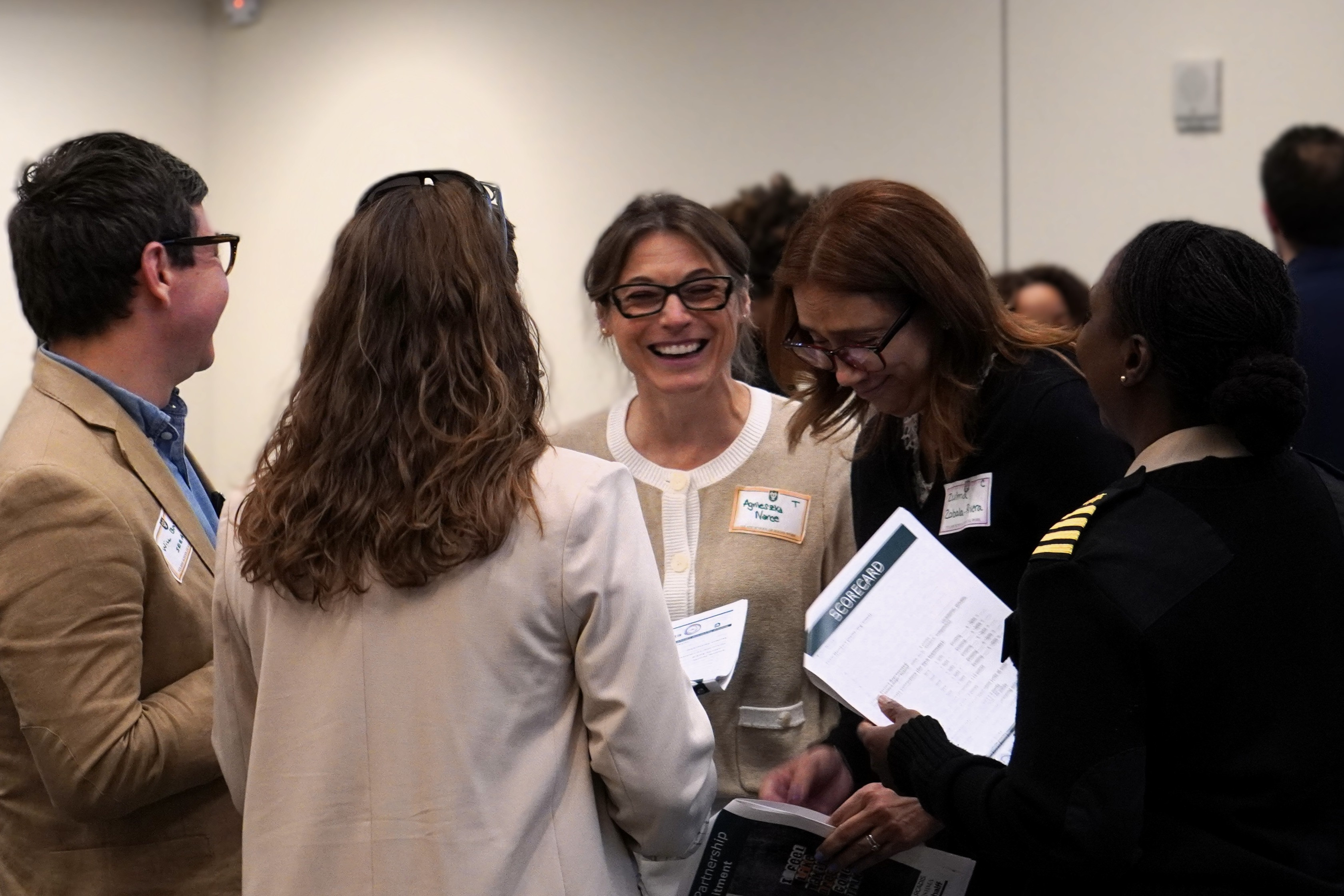 Smiling professionals conversing at a networking event; one woman wears a dark uniform.