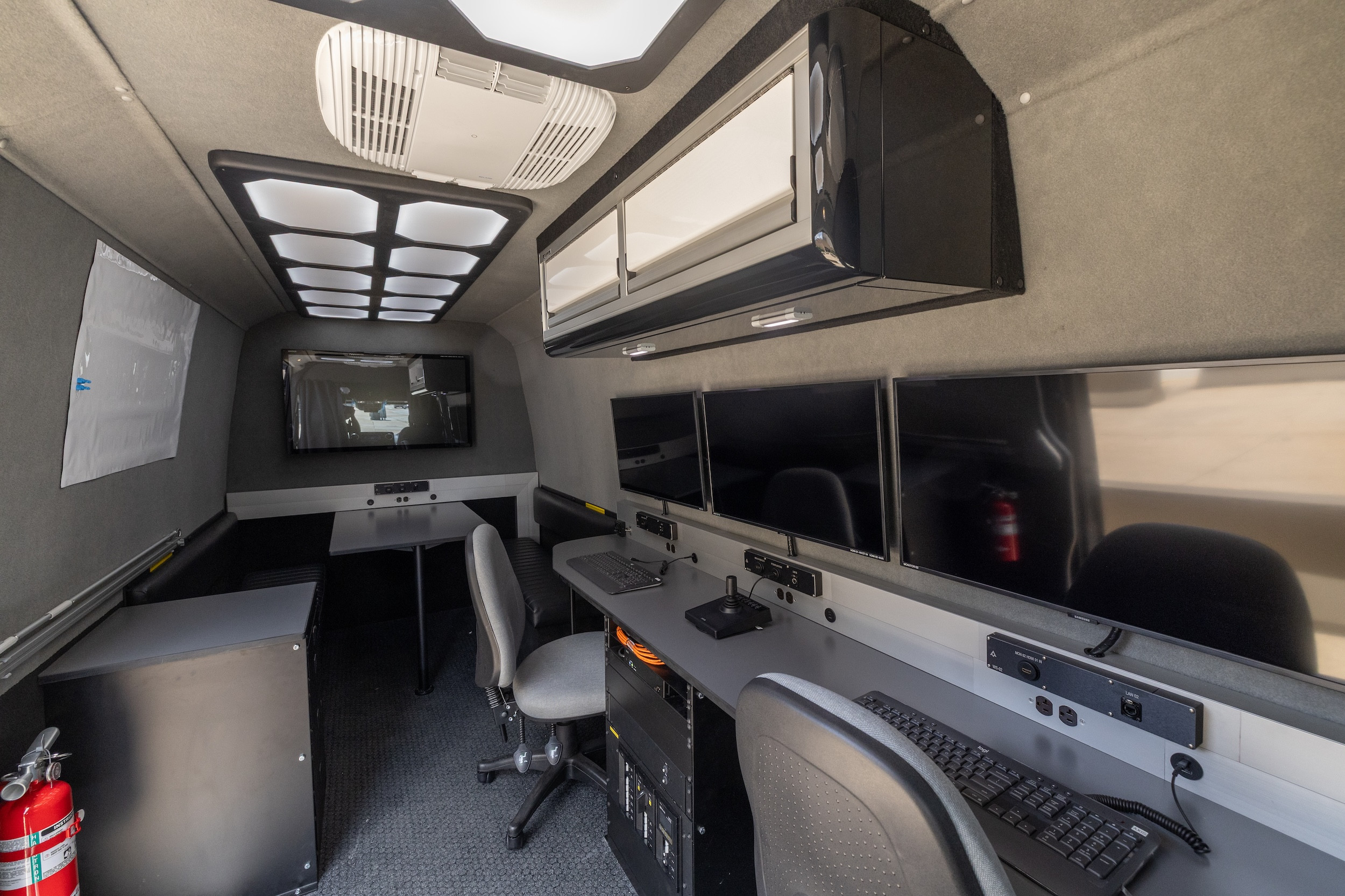 Interior of a mobile command unit with several monitors and workstations.