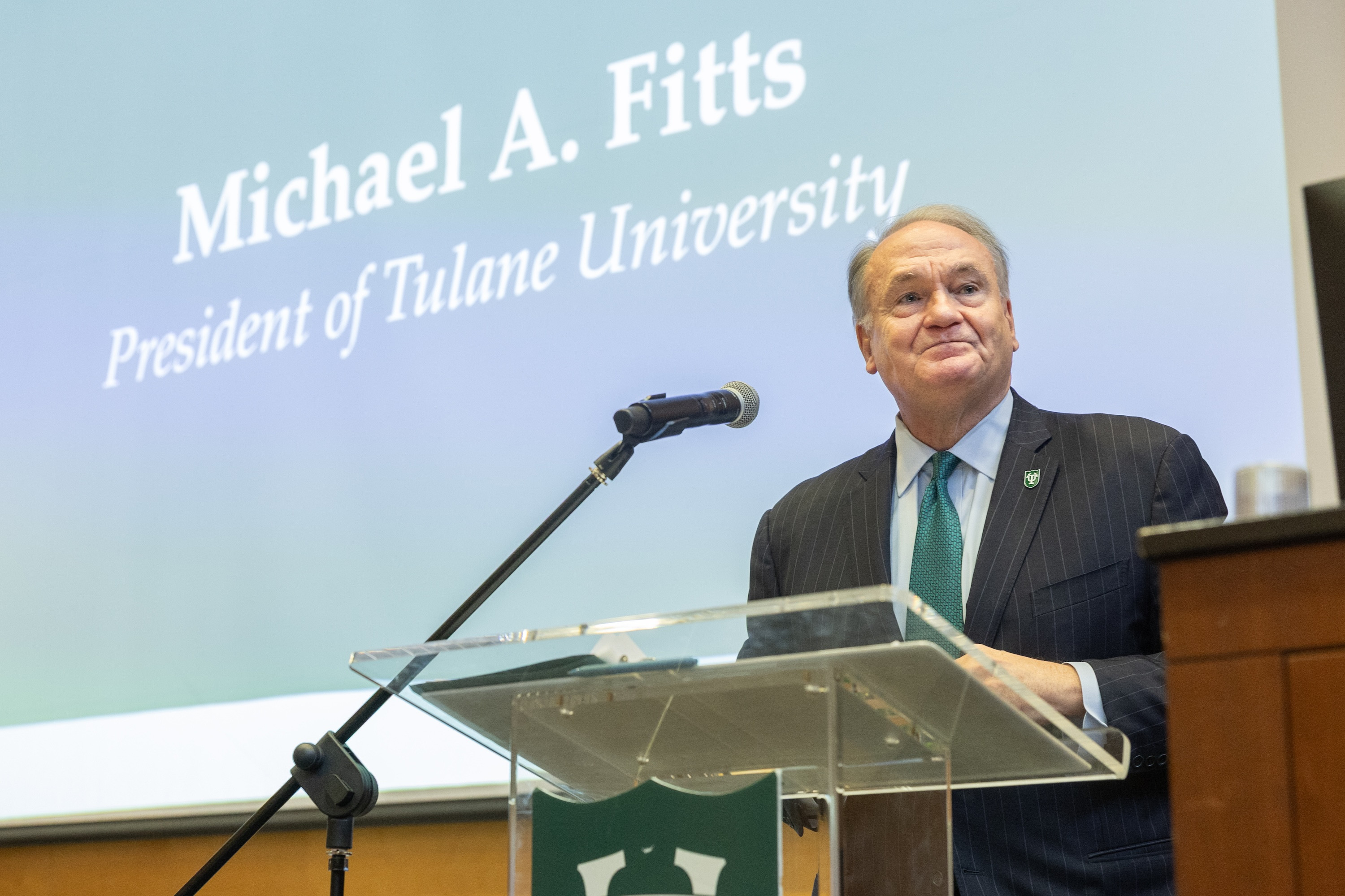 Michael A. Fitts, President of Tulane University, smiles at a podium.