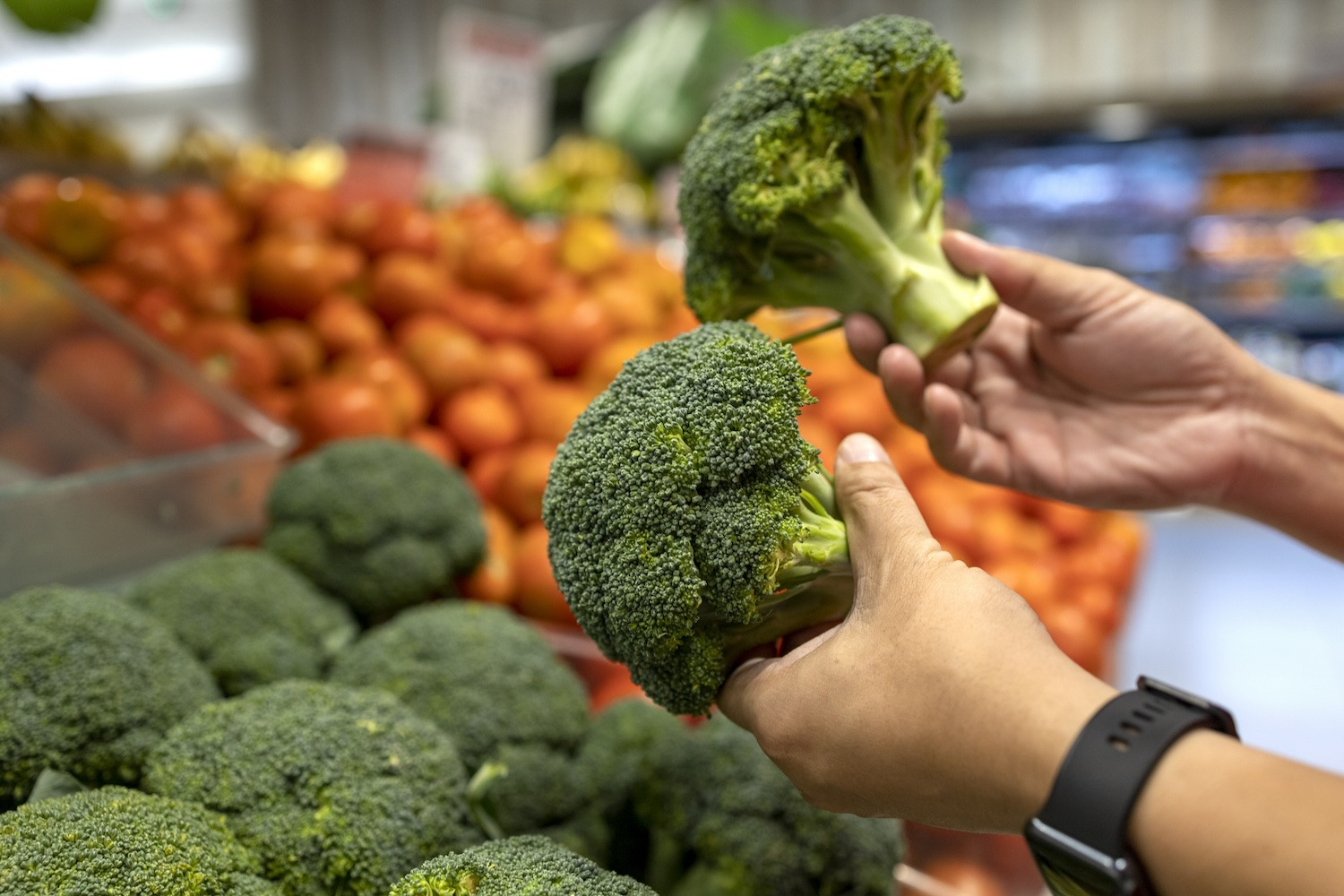 Man selects broccoli at store