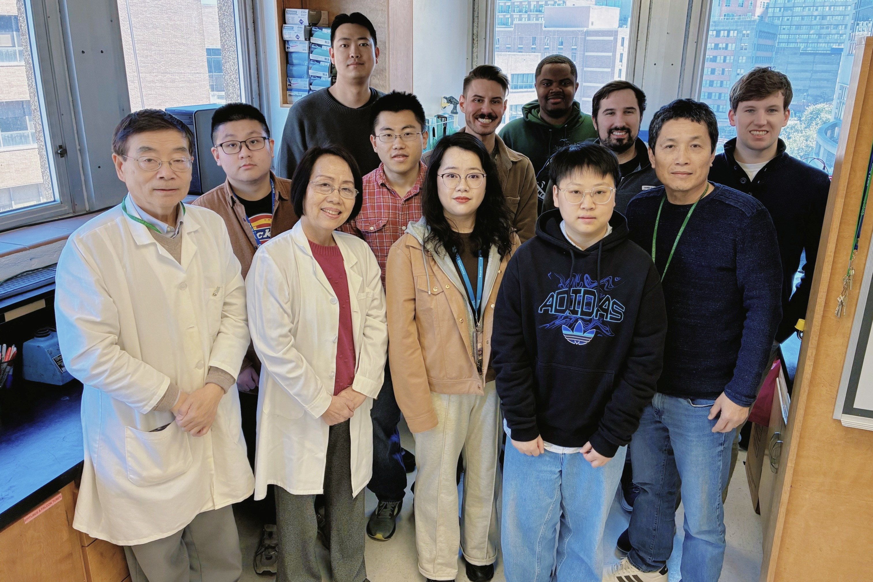 Eleven researchers, some in lab coats, pose together in a bright laboratory.