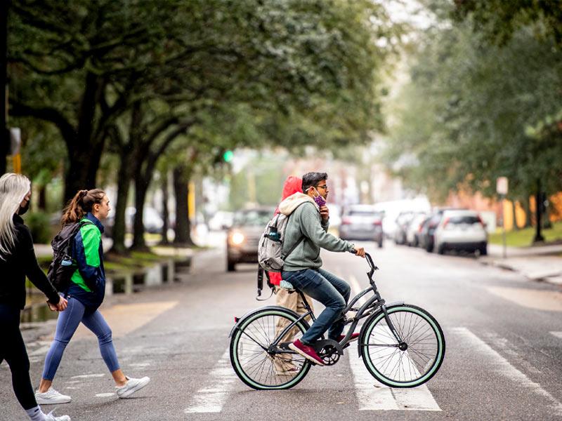 A student bike across Freret Street on the uptown campus during the light rain. 