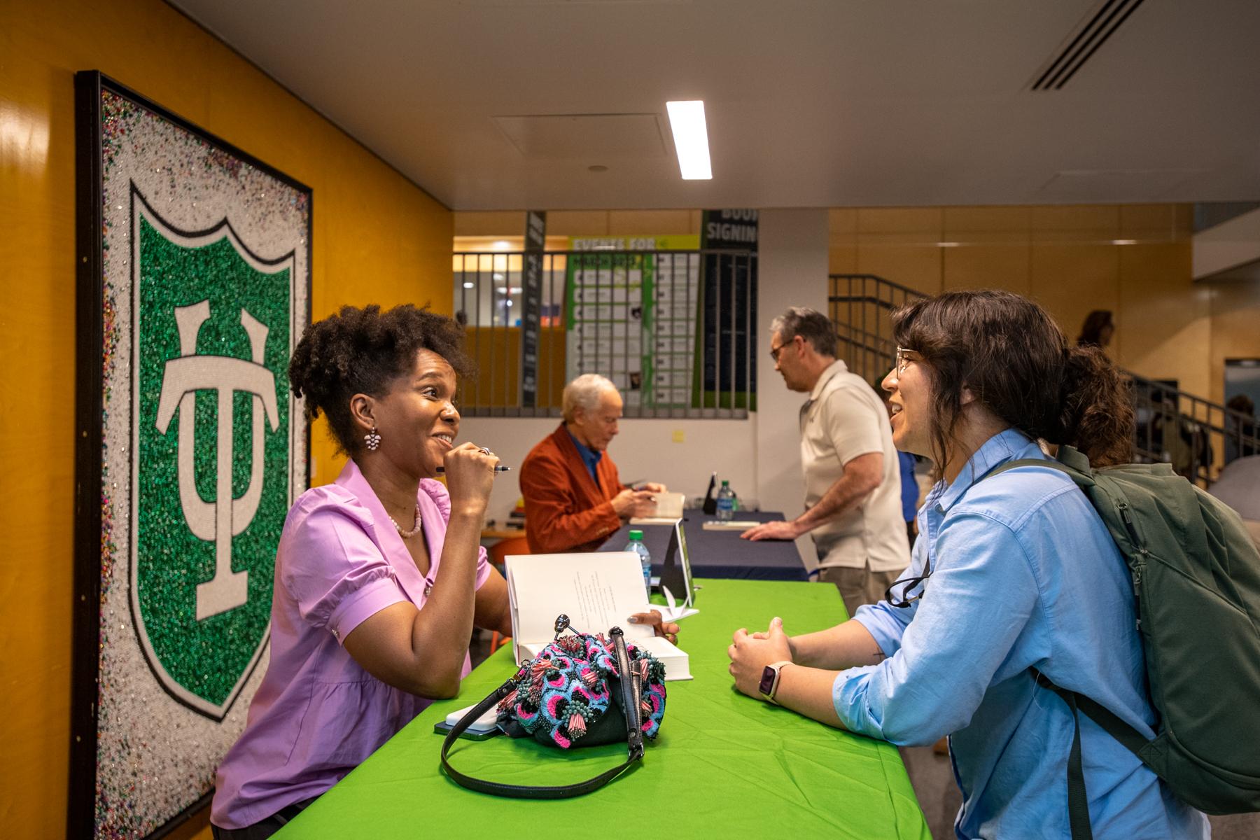 Imani Parry, far left, and Richard Ford, left, sign books in the Pedersen Lobby.