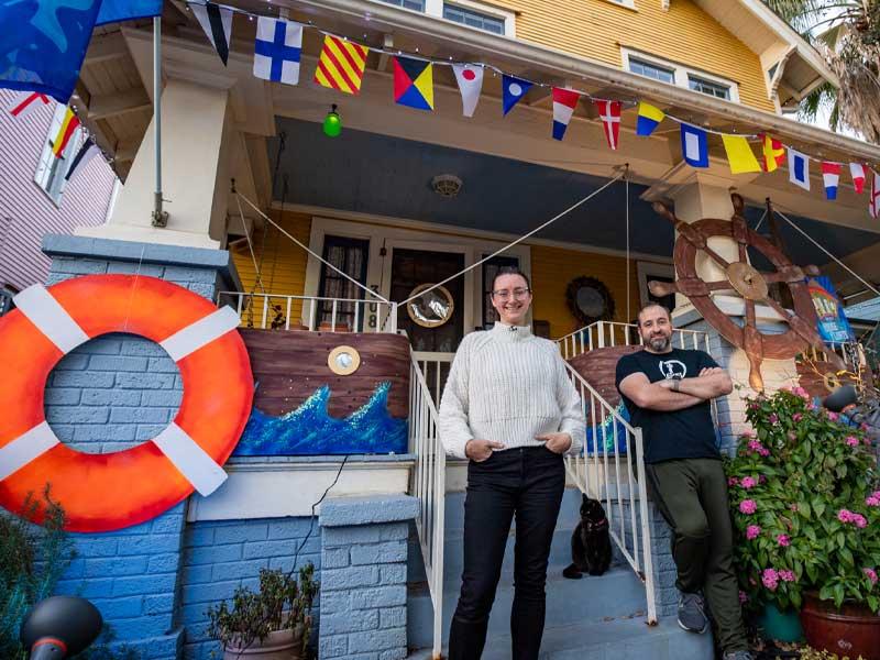 Krewe of House Floats Founder Megan Boudreaux, Opal the cat, and husband Allen outside their USS House Float in Algiers Point