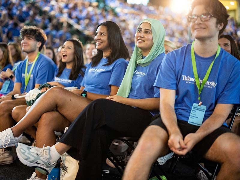 Cheerful students listen in to university leader remarks. 