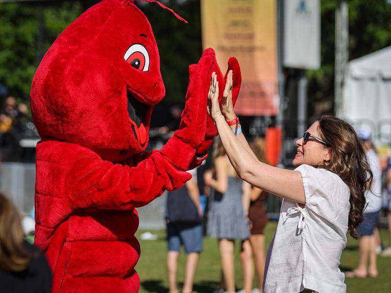 Carl, the Crawfest mascot, high fives Heidi Johnson, the mother of 3rd year student, Teigen Johnson.