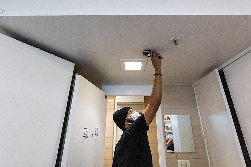 Mohammed Kahn, a supervisor with Servpro, checks for moisture in room at Monroe Hall.