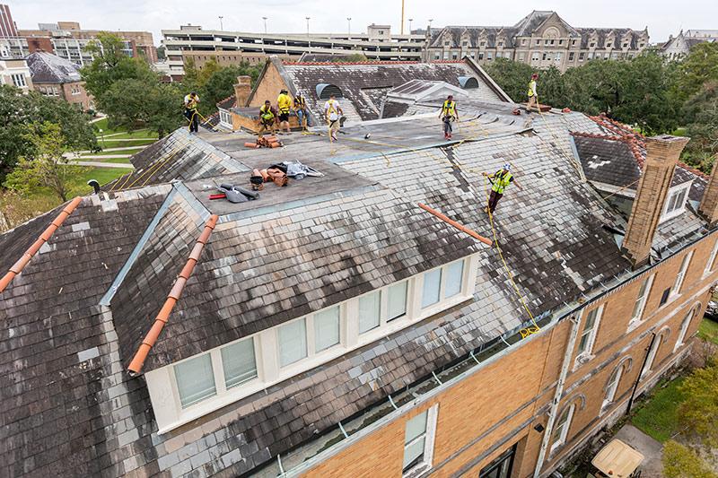 Contractors work on the roof of Hebert Hall. 