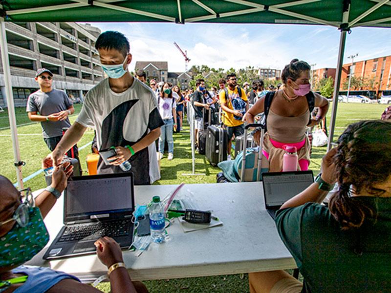 Students show their IDs to check-in before boarding buses. 