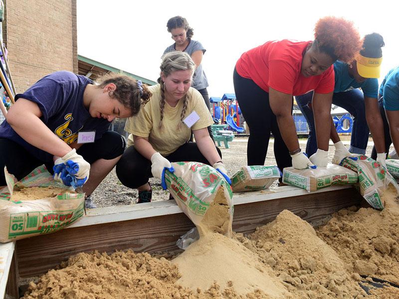 Tulane, Xavier and Loyola students work side-by-side to fill a sandbox at Homer Plessy School in the 7th ward during last year’s Martin Luther King Jr. Day of Service. (Photo by Cheryl Gerber)