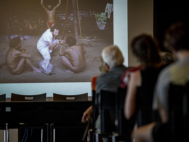 Lecture attendees view photo of ethnobotanist Mark Plotkin with Native tribal members