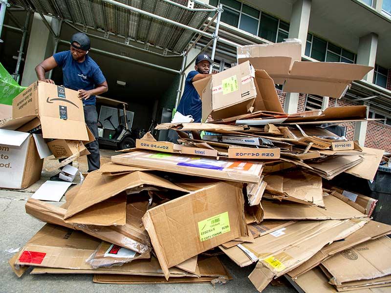 Kyshondra Sawyer, left, and Ricky Nelson with Sodexo flatten shipping boxes behind Monroe Hall on the first day of move-in.