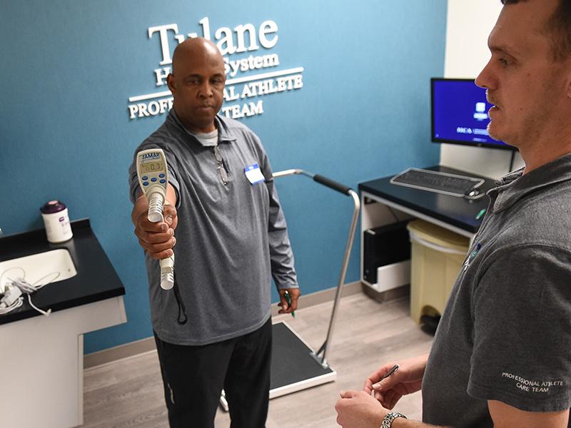 PACT lead athletic trainer Will Keller (right) works with former New Orleans Saints All-Pro running back Dalton Hilliard (left) during a recent screening for former NFL players at the PACT clinic. (Photo by Parker Waters)