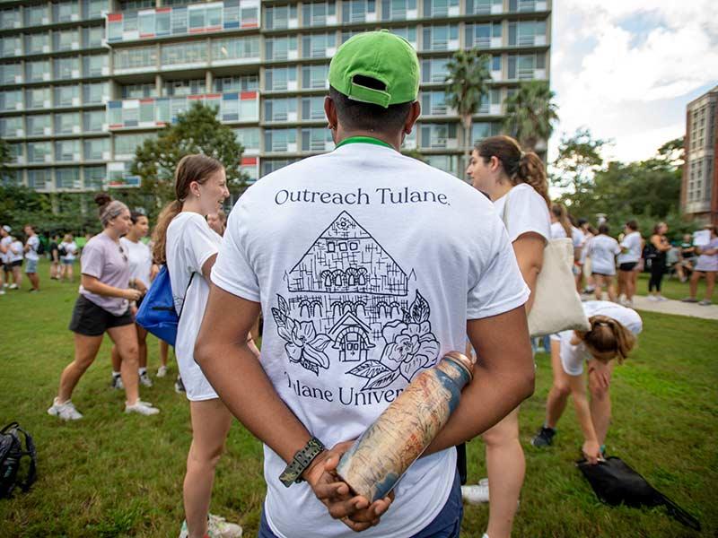 Akhil Chandran, a graduate student in the School of Public Health and Tropical Medicine chats with other Outreach volunteers as they wait to board buses that will take them to service partner locations throughout the New Orleans metro area.