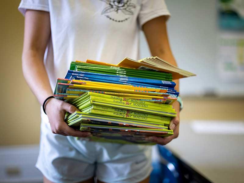 Kat Holtz carries an armload of books at Start the Adventure in Reading (STAIR) in Uptown New Orleans.