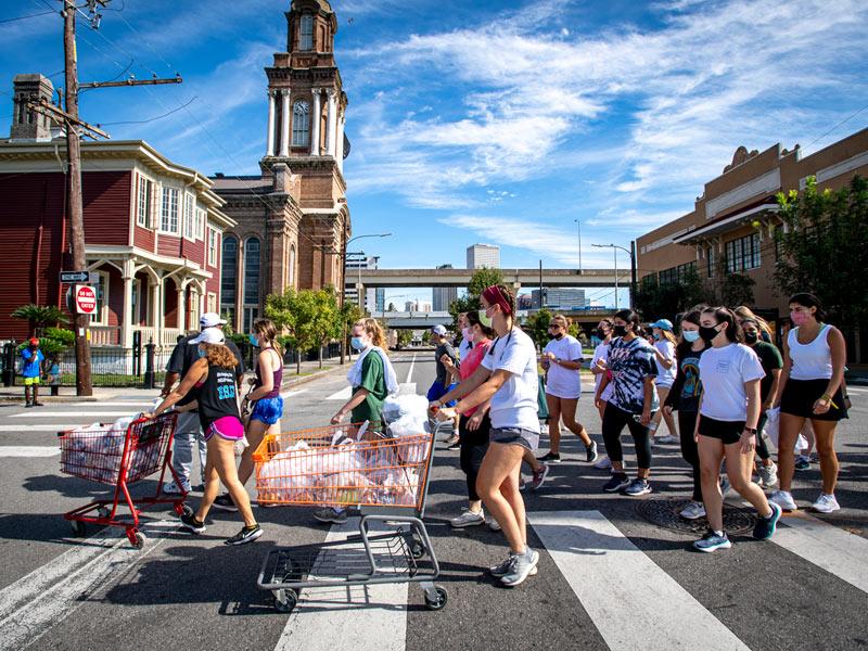 Students cross Oretha Castle Haley Boulevard to distribute bag lunches to individuals experiencing homelessness in the Central City neighborhood. The group effort was part of Outreach Tulane.