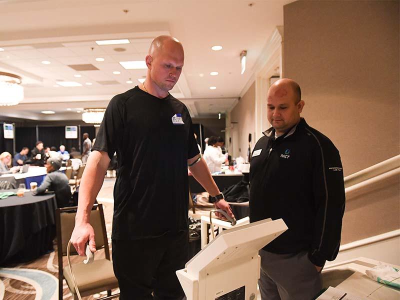 Former NFL player Steve Herndon (left) goes through a health assessment on the InBody under the supervision of PACT athletic trainer Scott Hebert (right) during a patient health screening at Super Bowl LIII in Atlanta. (Photo by Parker Waters)