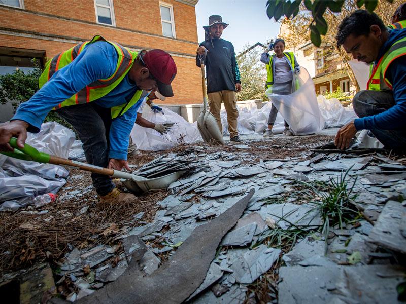 A work crew gathers broken roof shingles fallen from Hebert Hall. Contract workers from around the country assisted in hurricane remediation efforts.