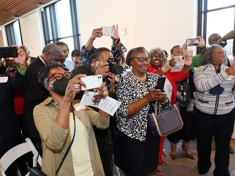 Family and friends applaud and take pictures as the portrait is unveiled.