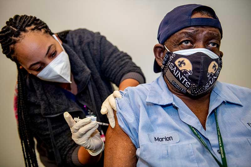 Marion Young with Tulane’s Downtown Facilities Services sits as he receives his first dose of the vaccine.