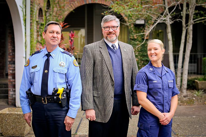 Graduates Lieutenant Mark Mulla (left) of the New Orleans Police Department and Lieutenant Marina Turner (right) from the United States Coast Guard stand with Michael Wallace (center), director of Tulane’s Emergency and Security Studies. (Photo by Jennife