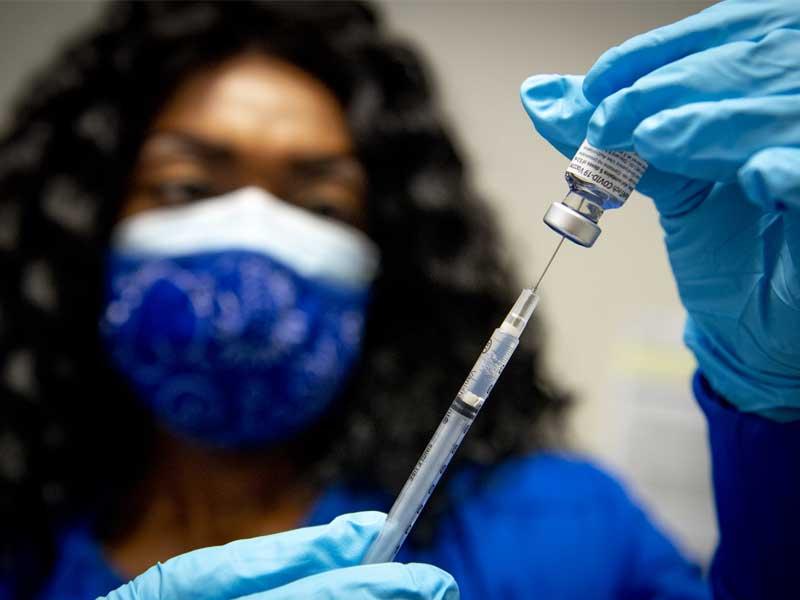 Nurse Kia Arbuthnot fills a syringe with the COVID-19 vaccine. 