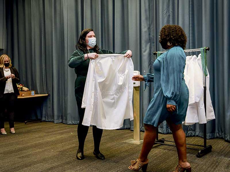 Taylor Dubose-Harris receives her coat from instructor Natalie Rolf